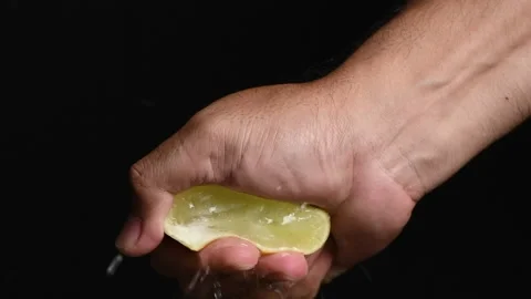 An anonymous hand squeezing a juicy lemon wedge Stock Footage 207472274