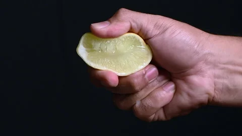An anonymous hand squeezing a juicy lemon wedge Stock Footage 207475494