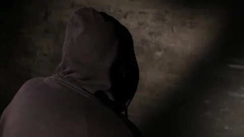 Anonymous hooded hacker with back to camera during police interrogation in .. Stock Footage 320622636