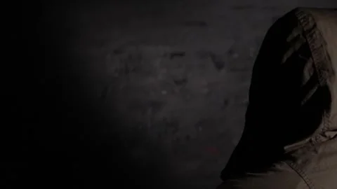 Anonymous hooded hacker with back to camera during police interrogation in .. Stock Footage 324955878