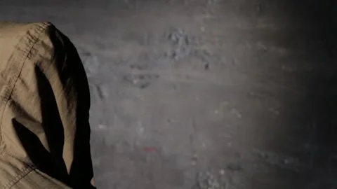 Anonymous hooded hacker with back to camera during police interrogation in .. Stock Footage 324955967