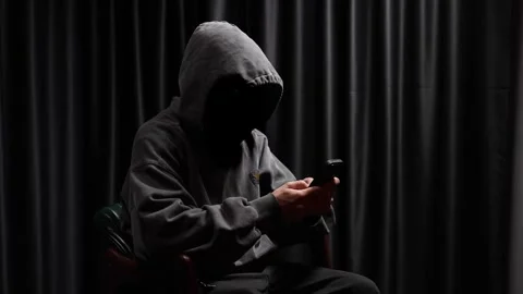 Anonymous hooded hacker using a smartphone in the dark Stock Footage 318584978