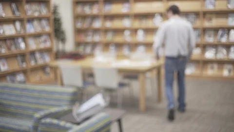 Anonymous Librarian Walks Through Library Looks At Book On Table Stock Footage 88016749