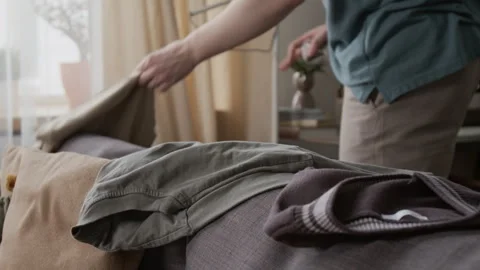 Anonymous Man Grabbing Clothing Items off Couch after Wiping Work Desk Stock Footage 335158723
