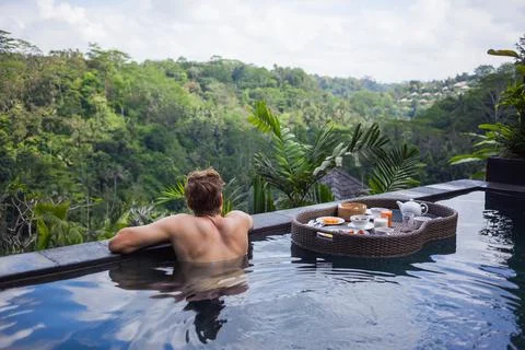 Anonymous man hanging on pool side border looking into the jungle thick while a Stock Illustration