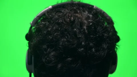 Anonymous man head shot from behind with headphones on green screen background Stock Footage 129465509