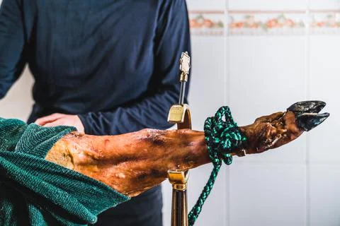 Anonymous man preparing a leg of ham in the kitchen at home. Putting the ham  Stock Photos