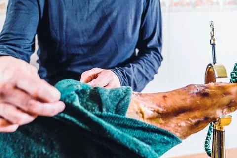 Anonymous man preparing a leg of ham in the kitchen at home. Putting the ham  Stock Photos