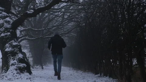 Anonymous man running along a dark snowy path Stock-Footage 146177957