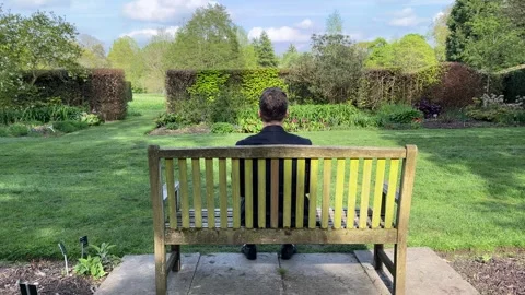 Anonymous man sitting on a bench - view from the back - solitude Stock Footage 240130528