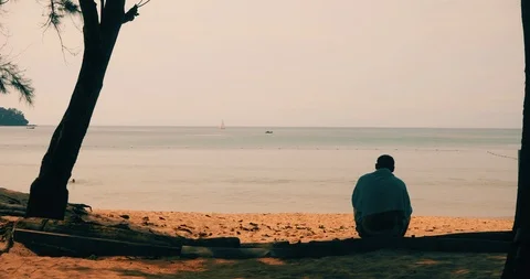 Anonymous man sitting on sandy beach Stock Footage 99755902
