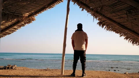 Anonymous man standing under wooden shed gazing to the ocean Stock Footage 172044578