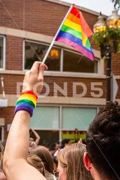 Anonymous man is waving a rainbow flag and wearing a rainbow wristband Gay Pride Stock Photos