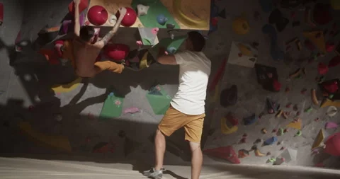Anonymous men practicing climbing wall in gym Stock Footage 259986063