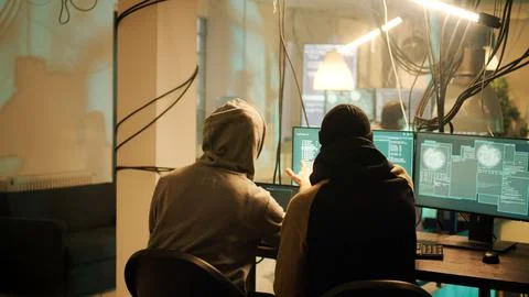 Anonymous men working together to break network system on computer Stock Photos