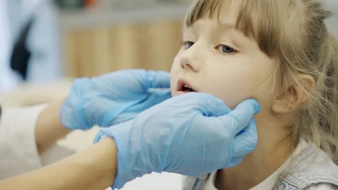 Anonymous pediatrician checking lymph nodes and throat of girl Stock Footage 103473539