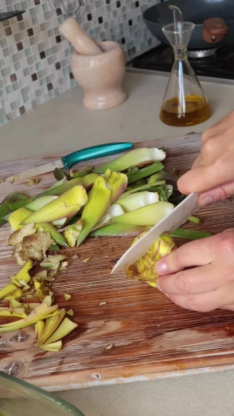 Anonymous person peels artichoke in kitchen at home. Healthy eating and Stock Footage 320451685
