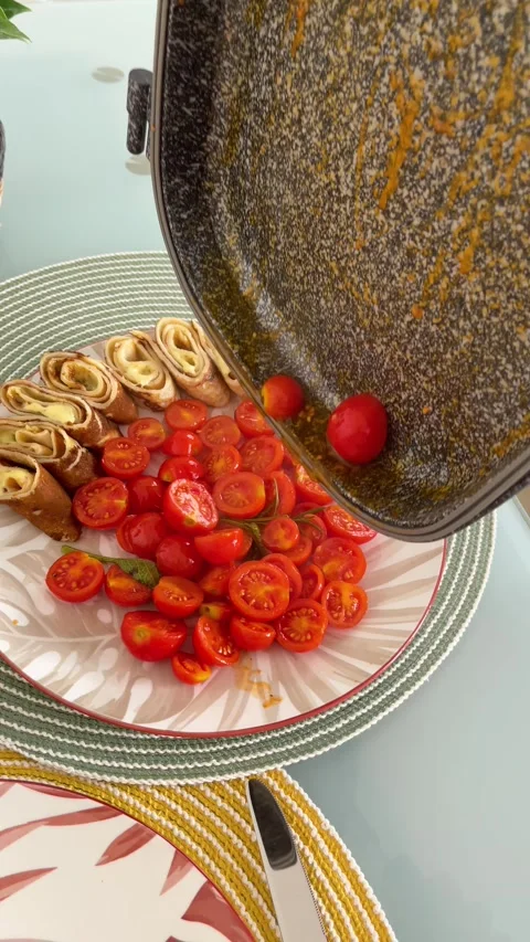 Anonymous person transfers roasted cherry tomatoes from rectangular pan to plate Stockbeeldmateriaal 318594372
