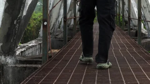 Anonymous person walking across a weathered pedestrian bridge 스톡 동영상 337928306