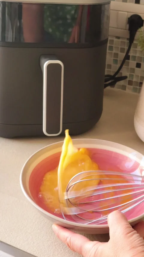 Anonymous person whisks egg at home. Air fryer on kitchen counter. Farm products Stock Footage 320154915