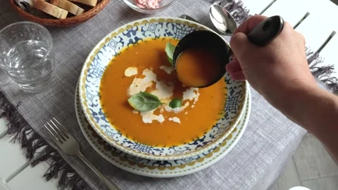 Anonymous pouring pumpkin soup into blue patterned porcelain plate. Homemade Stock Footage 316214275