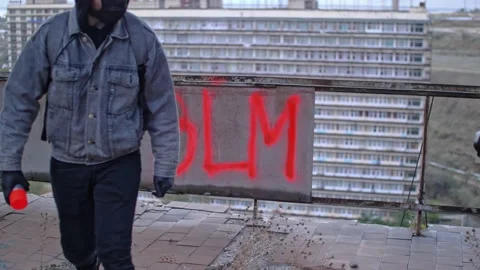 Anonymous protester hiding after making BLM graffiti on the wall Stock Footage 143349586