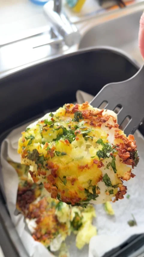 Anonymous put baked potato with fish to plate from air fryer. Healthy eating at Stock Footage 315549306