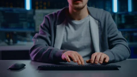 Anonymous Software Developer  Hacker Sitting at His Desk and Working on Computer Stock Footage 103576100