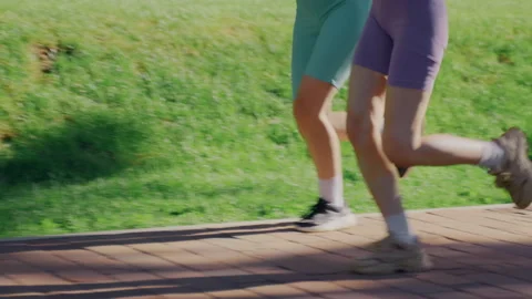 Anonymous Twin Runners Jogging Along Park Sidewalk in Colorful Sportswear 動画素材 336962629