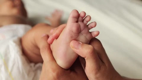 Anonymous unrecognizable mother’s hands moved tenderly over her infant’s tiny 库存影片 291303337