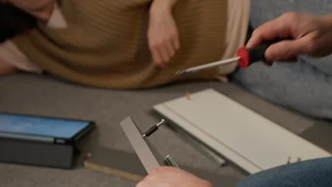 Anonymous Woman Chatting to Man Assembling Flatpack Drawer at Home Stock Footage 330511869