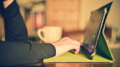 Anonymous woman sitting using tablet on dining room table in the evening Stock Footage 145846083