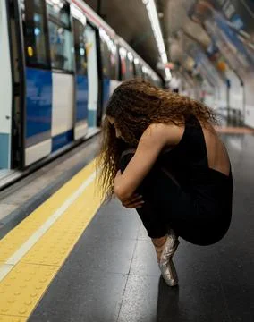 Anonymous young ballerina sitting on tiptoe on metro platform Stock Photos