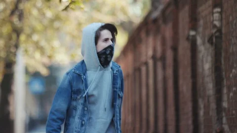 Anonymous young man in balaclava standing by the wall and holds spray paint. Act Stock Footage 105246758