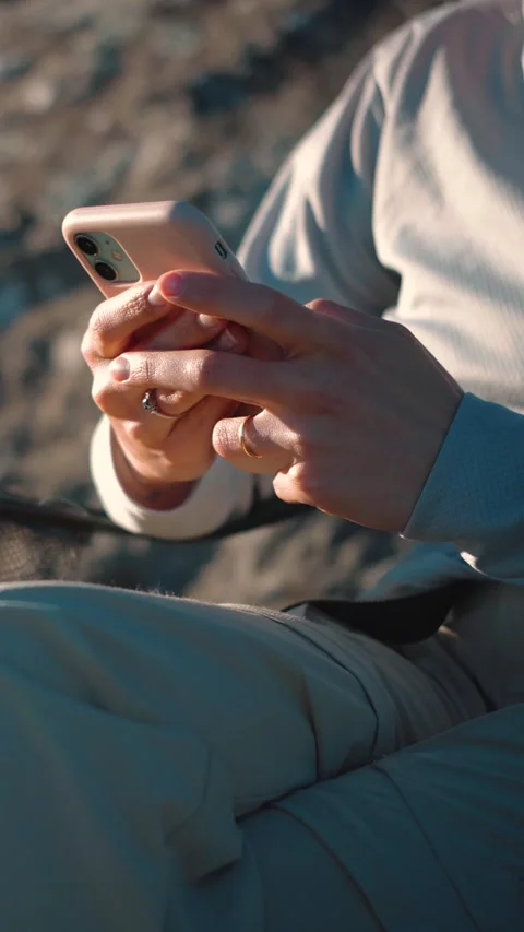 Anonymous young woman's hands using a smartphone outdoors in nature, representin Stock Footage 346655295