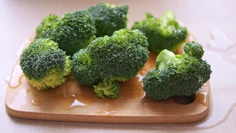 Another piece of broccoli is placed on cutting boar showing off vibrant green Stock-Footage 267197070