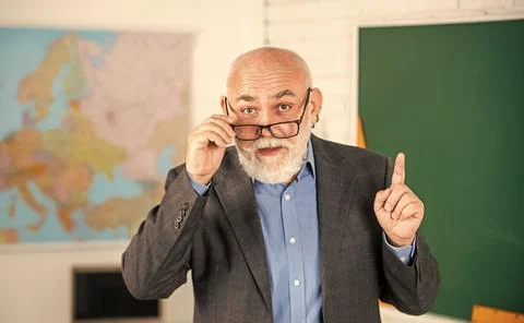 Answer and question. senior man teacher at blackboard. bearded tutor in glasses Stock Photos