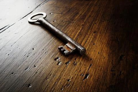 Answer, guess, solution to a problem concept. An old metal key lies on a wooden Foto stock