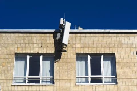 Antenna mobile operator on the wall on blue sky Stock Photos