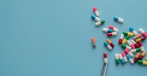 Antibiotic drug selection. Multi-colored capsule pills on blue background. Fo Stock-Fotos