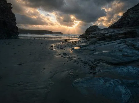 Anticlinal rays pierce the sunset clouds off Illas beach Stock Photos