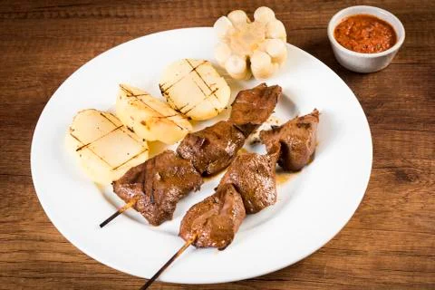 Anticuchos, Peruvian cuisine, grilled skewered beef heart meat with boiled po Stock Photos