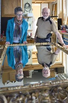 Antikschreiner und Kundin bewundern den fertig renovierten Barockspiegel u... Stock Photos