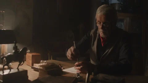 Antiquarian writing something down on a piece of paper on his desk Vídeo Stock 258296472