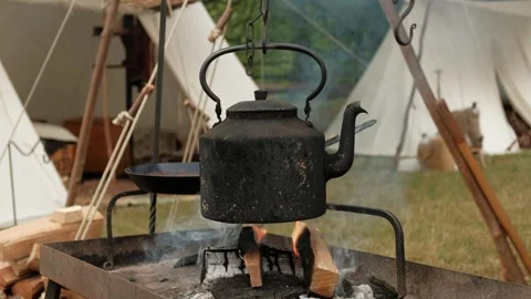 An antique black kettle is simmering on the fire in the tent city. Stock Footage 240465481