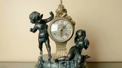 Antique bronze mechanical clock with angels on a stone base on a glass table Stock Footage 121604628