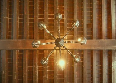 Antique chandelier hanging from the wooden ceiling. Bottom view. Stock Photos