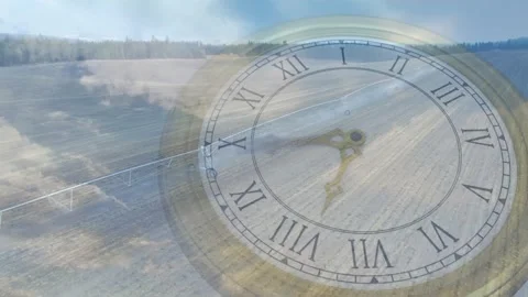 Antique clock face rotating over tilled field on drone pan, clouds shifting, Stock Footage 321099403
