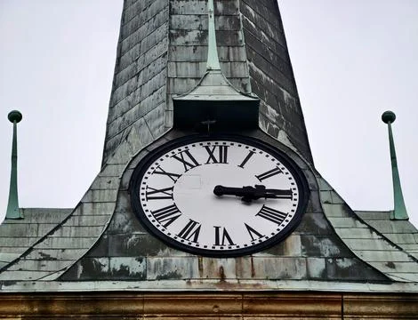 Antique clock face on weathered copper steeple with Roman numerals Stock Photos