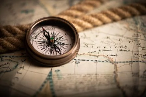 Antique compass lying on old style map Stock Photos